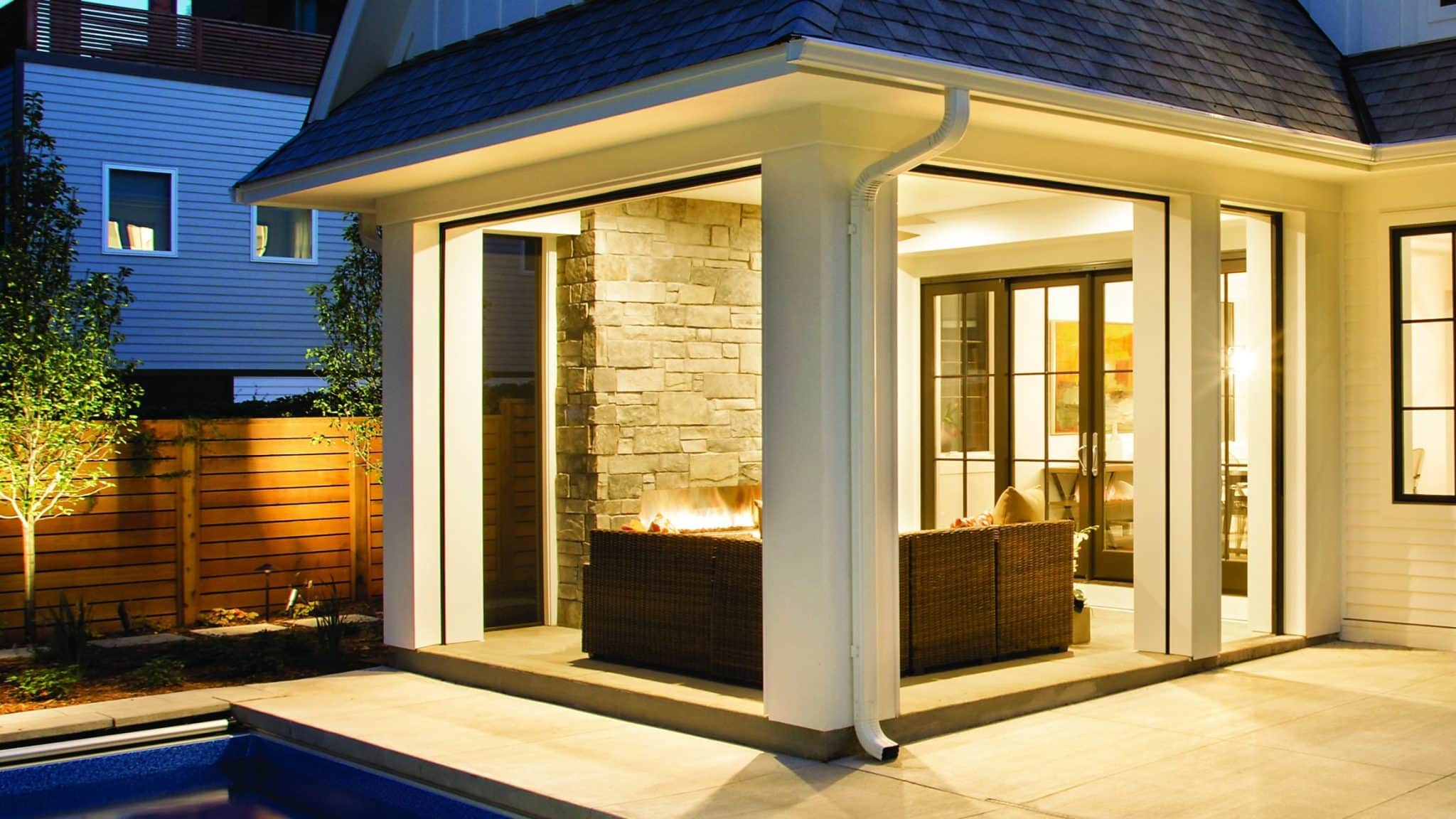 Infinity by Marvin picture windows and a sliding French door with an Ebony exterior on a poolside home at dusk